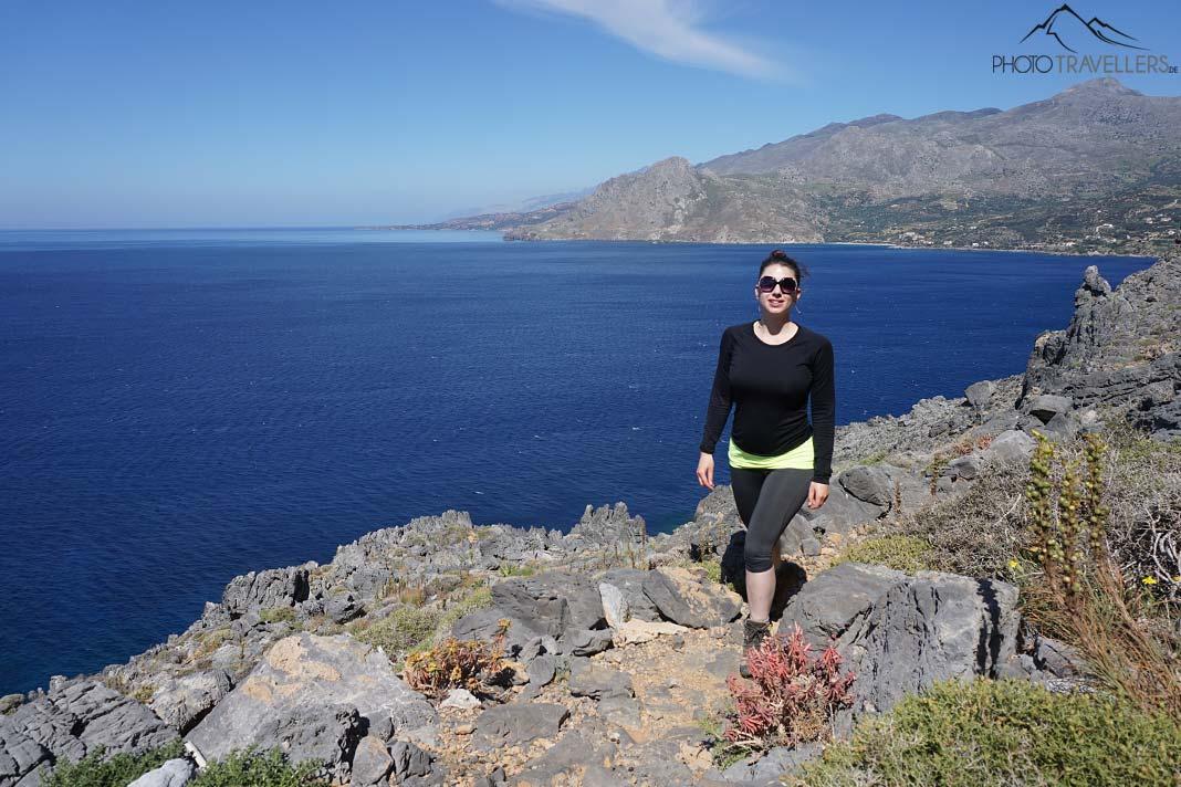 Blogueuse de voyage Biggi Bauer sur le sentier menant autour du cap Kako Mouri. En arrière-plan, la côte avec la mer bleue